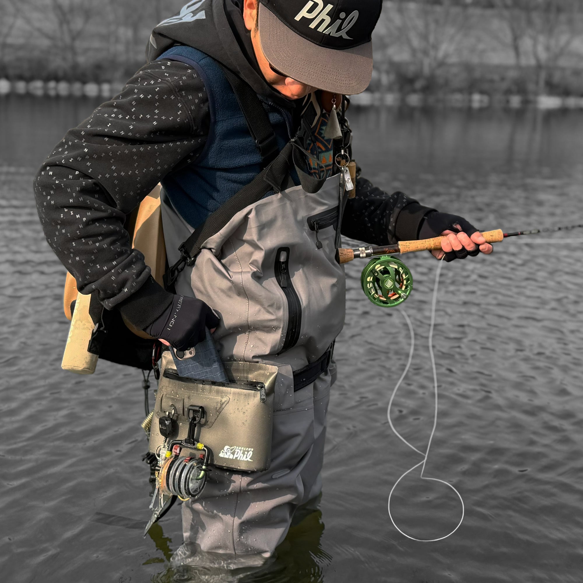 Angler wading in the river with the compact dry pouch secured close to the body
